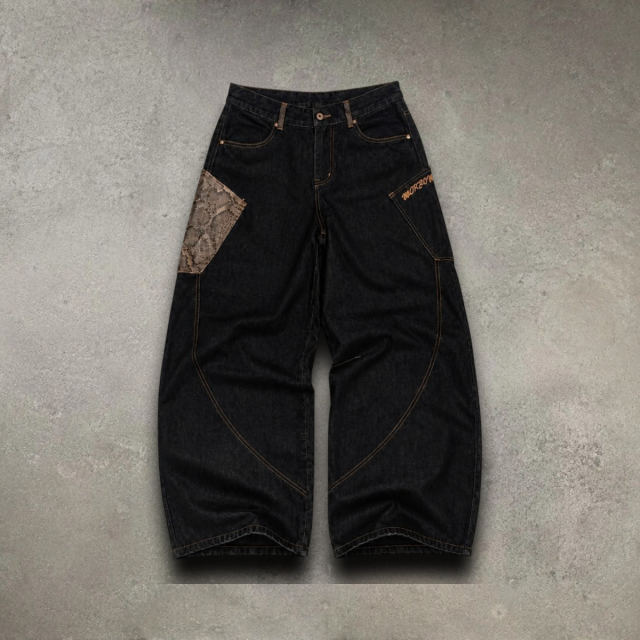 Black baggy jeans with a snakeskin pocket on a concrete-look background